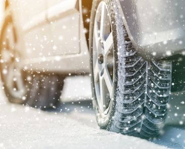 Close-up of car wheels rubber tires in deep winter snow. Transportation and safety concept.